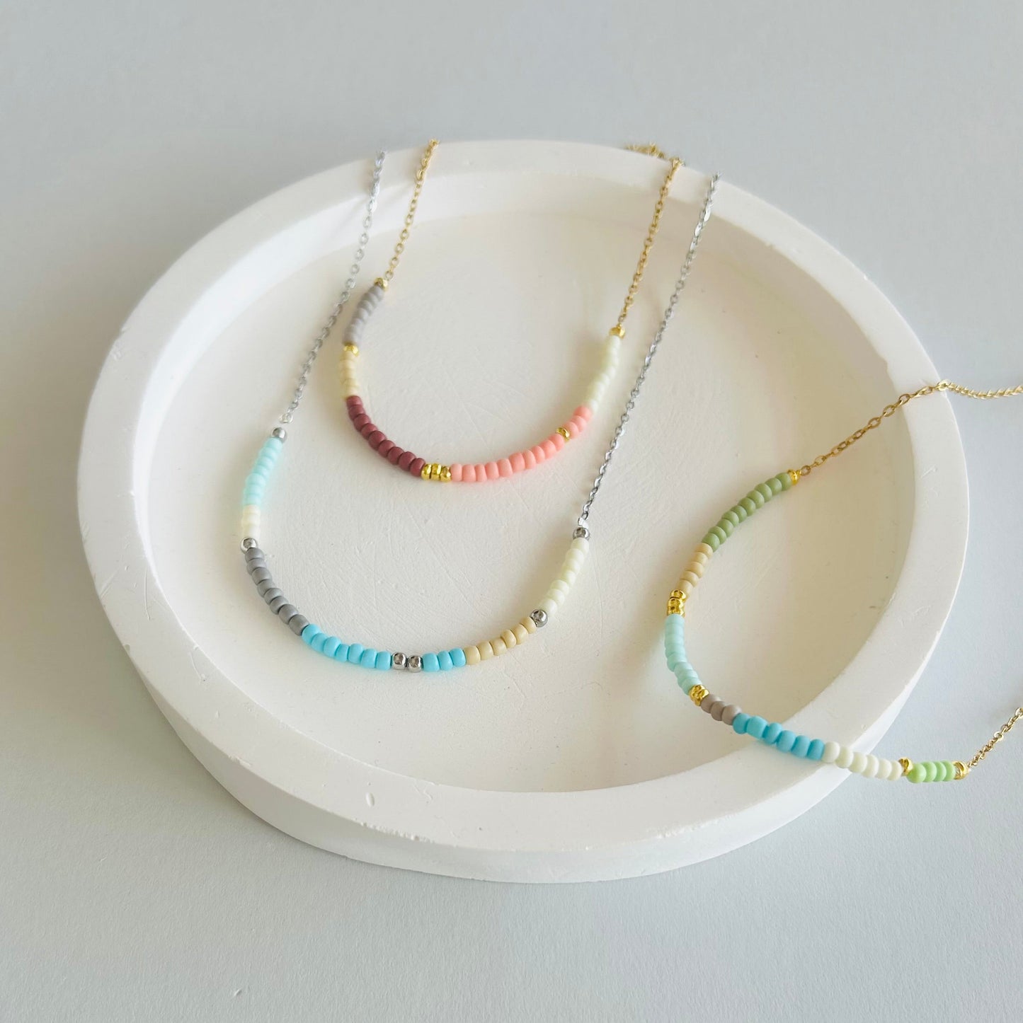 Three necklaces on a white dish with a plain background