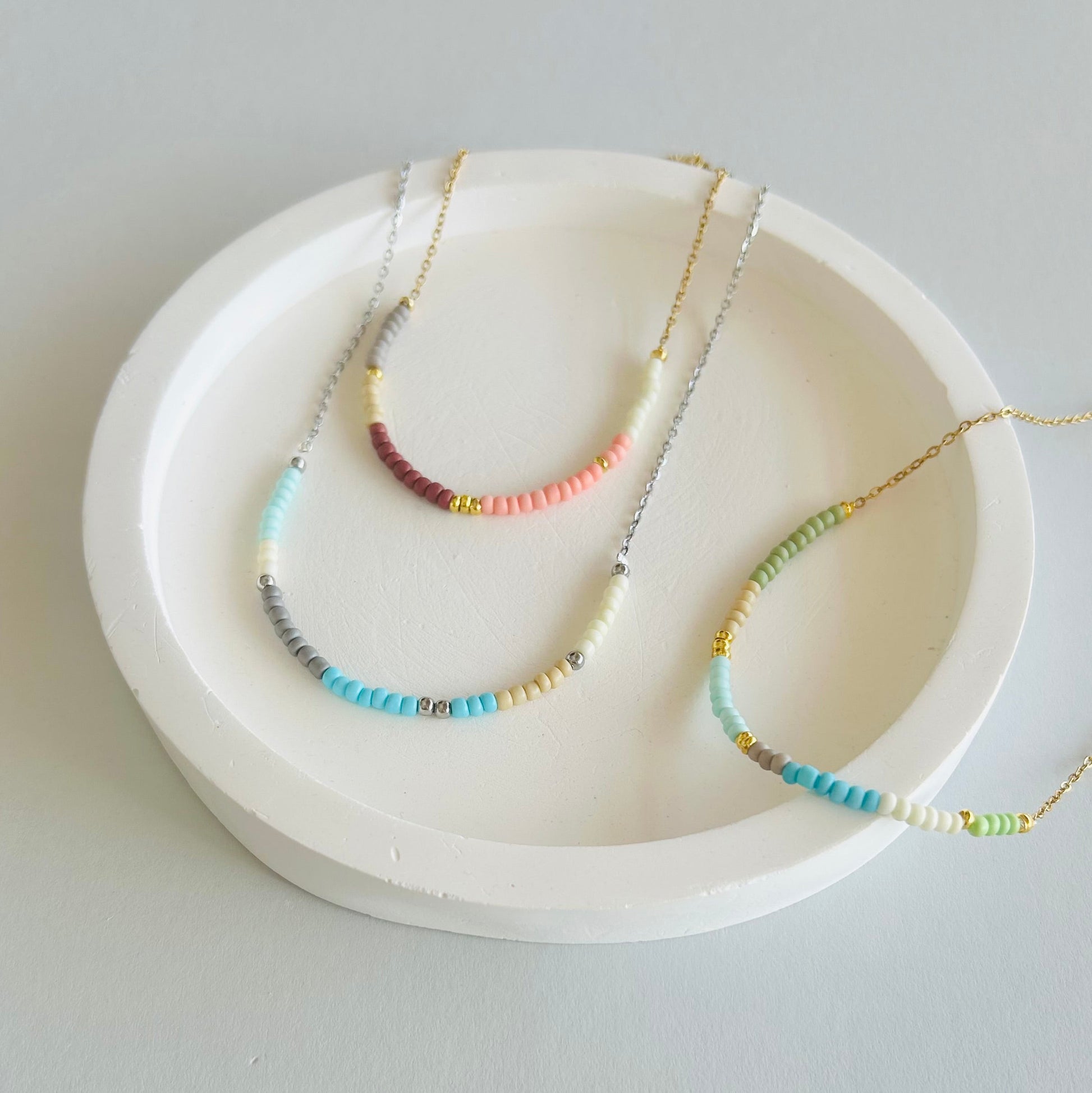 Three necklaces on a white dish with a plain background