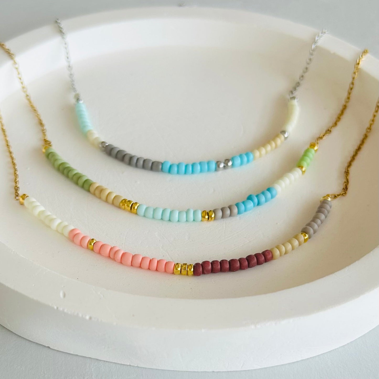 Set of colorful beaded necklaces on a white dish