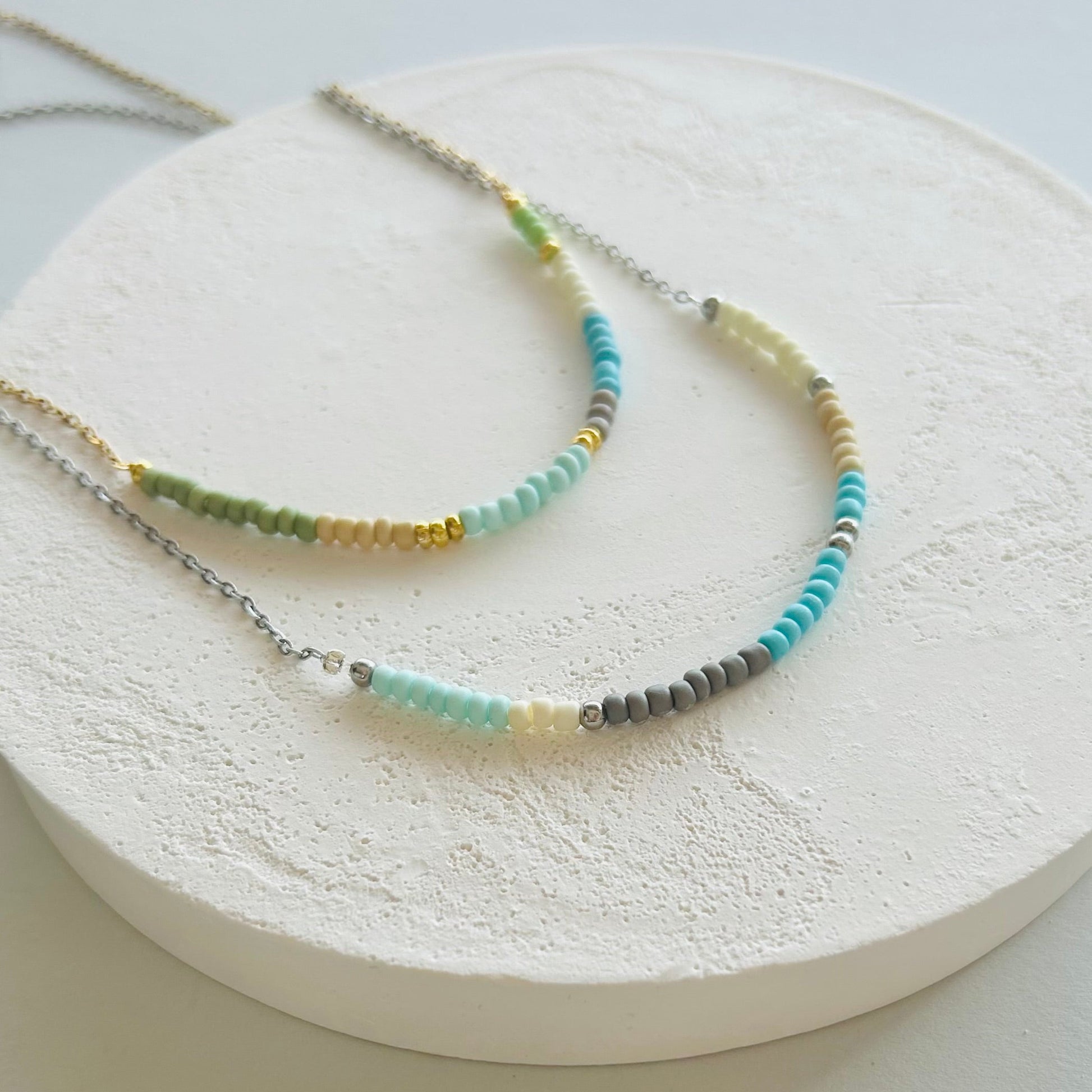 Two beaded necklaces on a round white stone surface