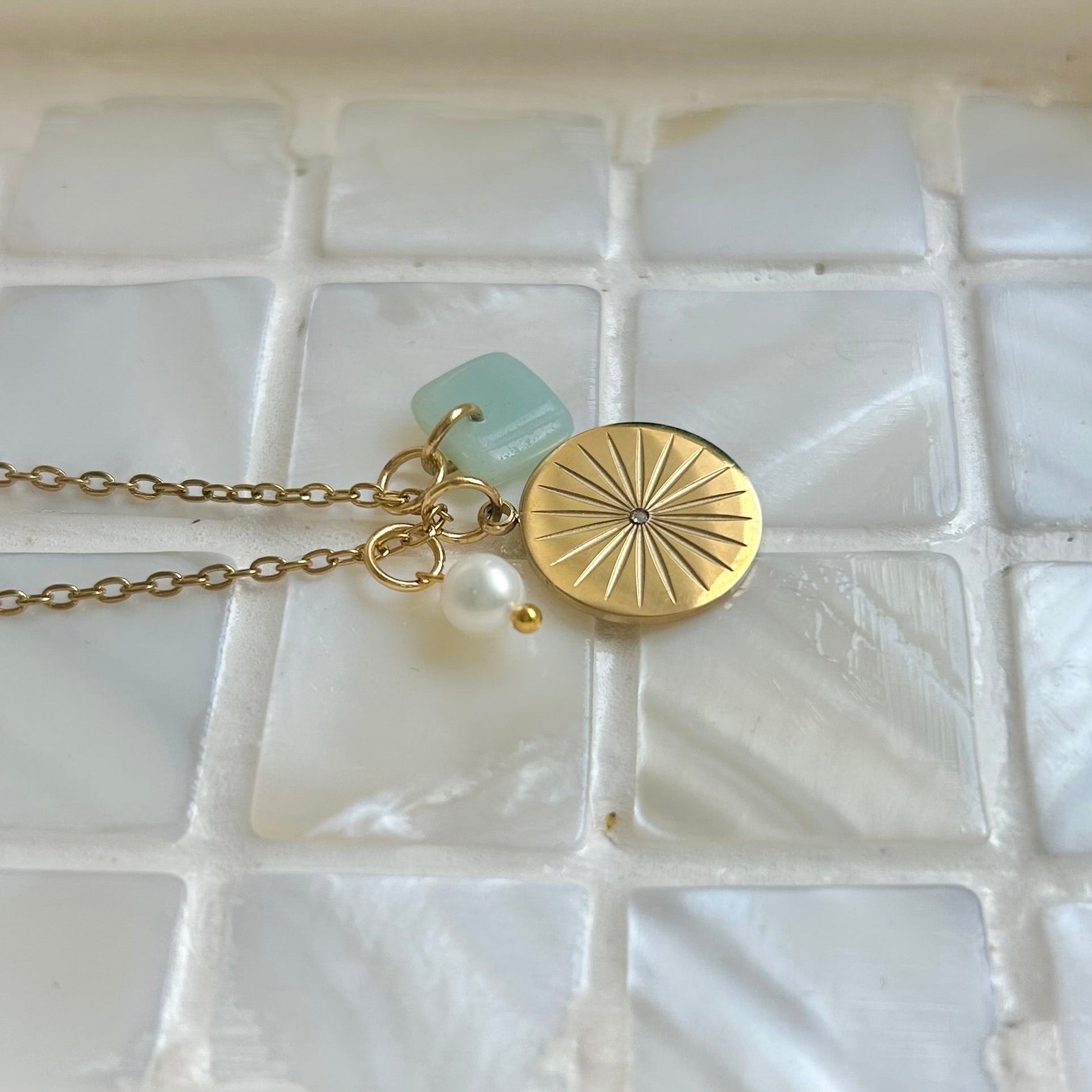 Gold necklace with a pendant on a textured white surface